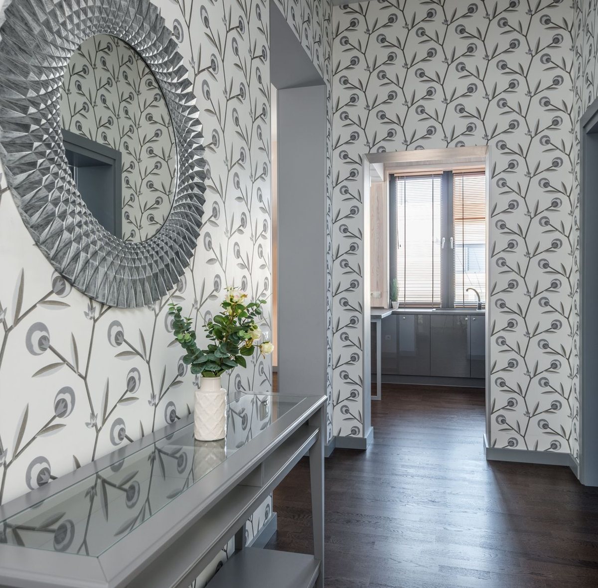 Entryway with a patterned wallpaper, a round mirror and a console table