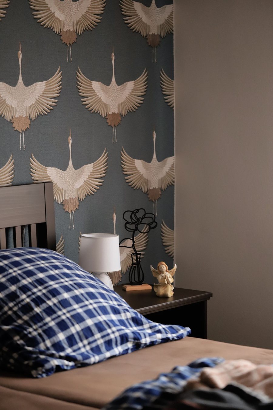 Bedroom with a moody blue crane-motif wallpaper feature wall
