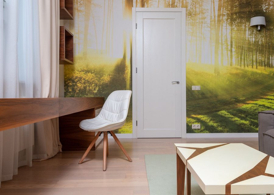 Home office with a soft woodland mural wallpaper behind a desk