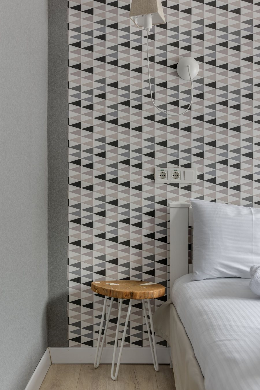 Bedroom corner with a grey geometric triangle wallpaper