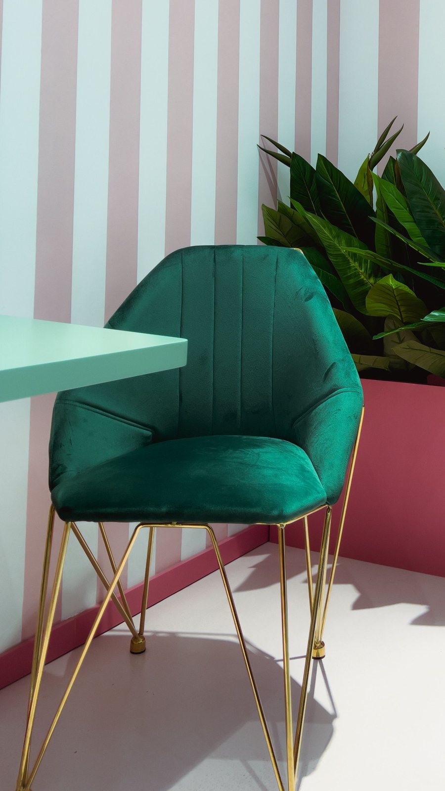 Reading corner with a striped wall and a green velvet accent chair