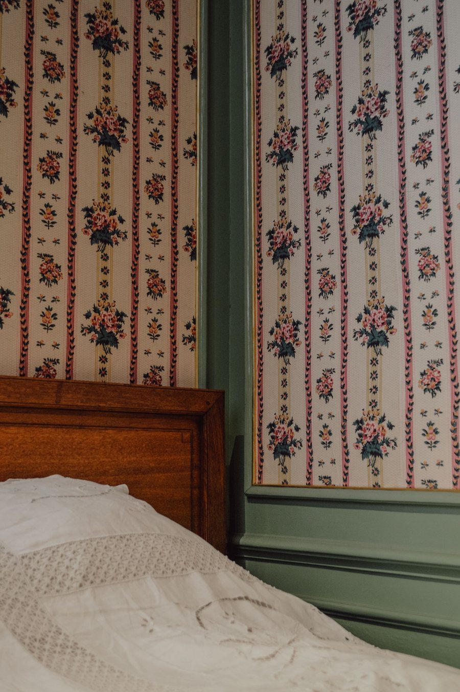 Bedroom with a vintage floral-and-stripe wallpaper beside a wooden bed
