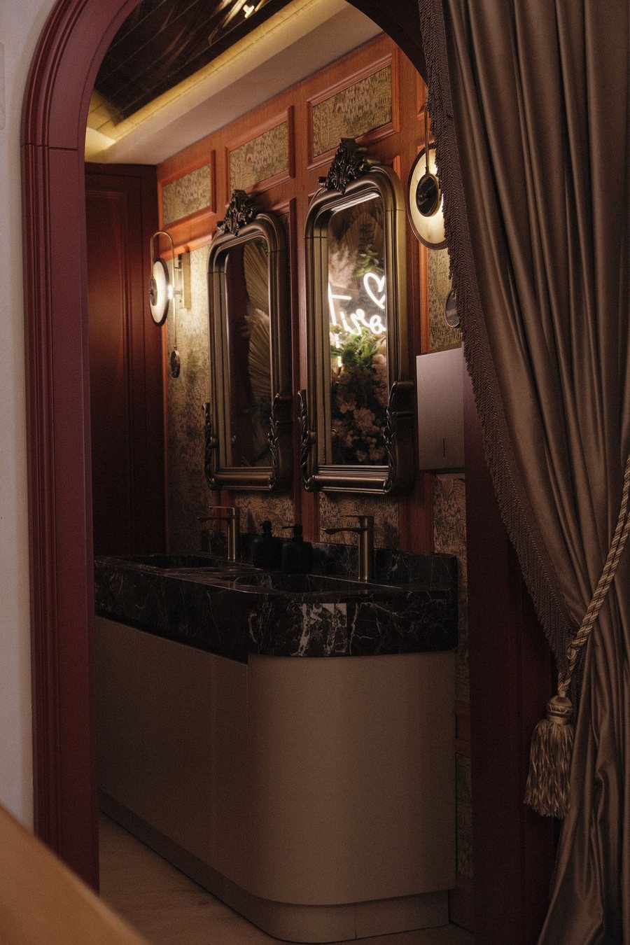 Elegant bathroom with ornate paneled walls, a framed mirror and marble sink